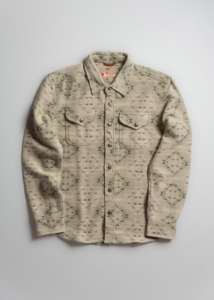 Tan patterned button-up shirt with two chest pockets, laid flat on a light gray background, showcasing its design and texture.