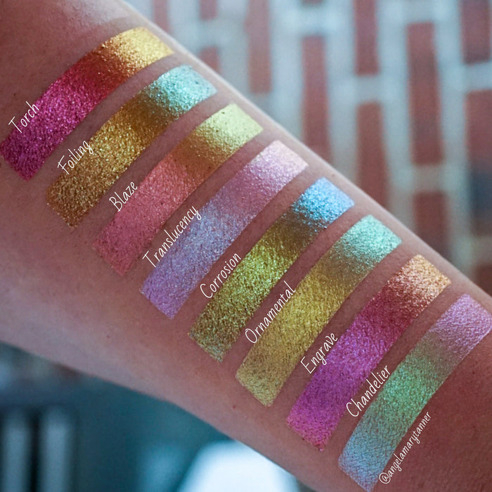 Bottom left angled arm swatches on fair skin tone of Blaze Glitter Multichrome Eyeshadow shifts compared to Torch, Ornamental, Corrosion, Foiling, Engrave, Chandelier