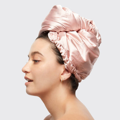 Side view of model wearing the Blush Satin Wrapped Hair Towel against a light gray background