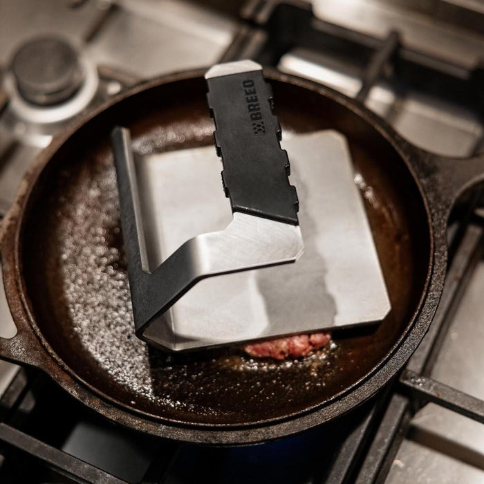 This is an image of a smash burger on a skillet pressed with a Breeo Griddle Press