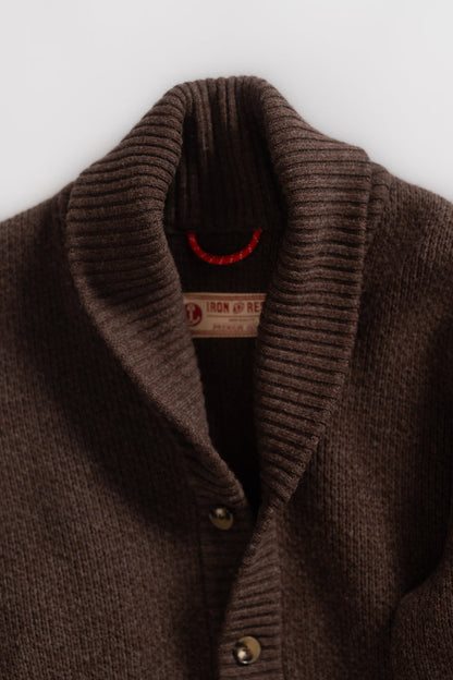 Close-up of a brown ribbed cardigan with a shawl collar and buttons, featuring an Iron and Resin label inside.