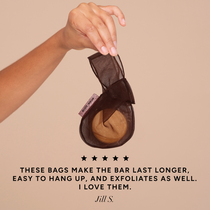 Hand holding the Kitsch Chocolate Body Wash Bar Bag with a 5-star customer review quote: "These bags make the bar last longer, easy to hang up, and exfoliates as well. I love them." – Jill S.