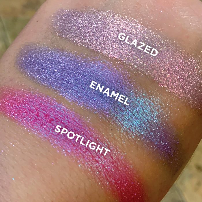 Top angled close up hand swatches on fair skin tone of Glazed Glitter Multichrome Eyeshadow shifts compared to Enamel, Spotlight