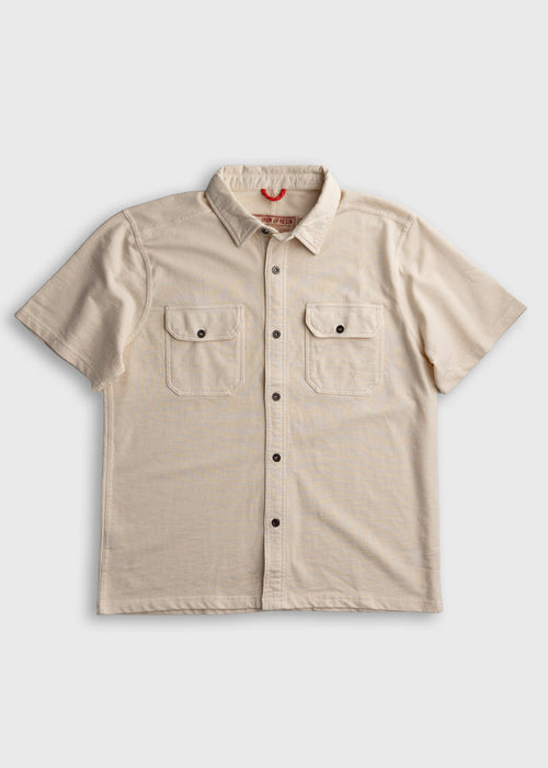 Beige short-sleeve shirt with button front and two chest pockets, laid flat on a white background.