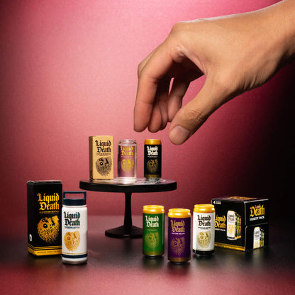 Hand reaching for a mini 'Liquid Death' product against a pink background