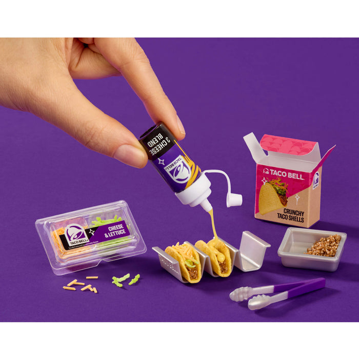 Miniature Taco Bell food set with hand pouring sauce on a purple background