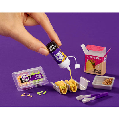 Miniature Taco Bell food set with hand pouring sauce on a purple background