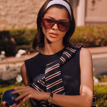 lifestyle - female holding a bocce ball wearing diff eyewear featuring the morgan oversized navigator sunglasses with a rugby red acetate frame and burgundy gradient lenses front view