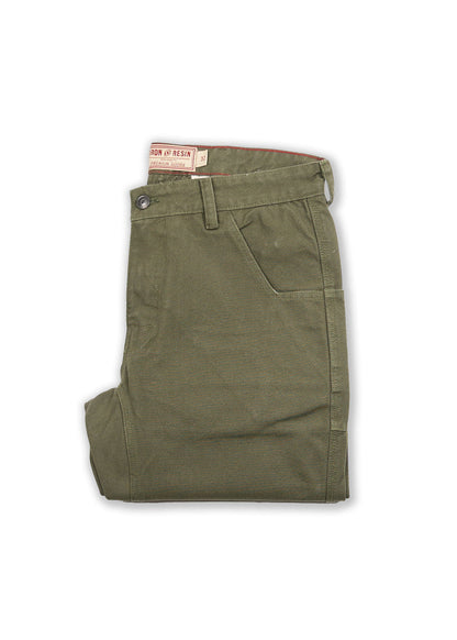 Olive green pants folded neatly, featuring a button closure and side pocket. Visible "Iron & Resin" label on the waistband.