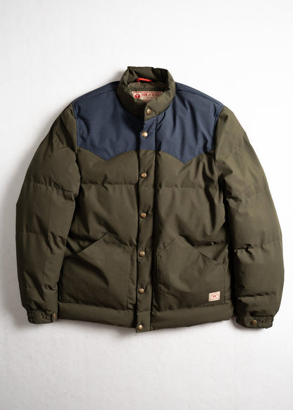 Green and navy puffer jacket with button closure, featuring two front pockets, displayed against a plain white background.