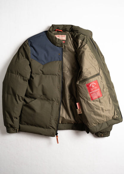 Green puffer jacket with blue shoulder patch, open to reveal beige lining and red label inside. Iron and Resin branding visible.