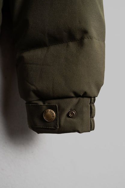 Close-up of a green jacket sleeve with a metal snap button labeled "Iron & Resin" against a neutral background.