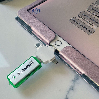 Green USB drive attached to a pink electronic device on a marble surface