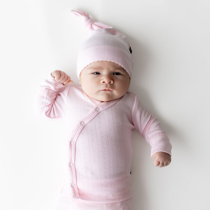 Close up of newborn wearing the Pointelle Take Me Home Set with Cap in Sakura with the picot trim visible