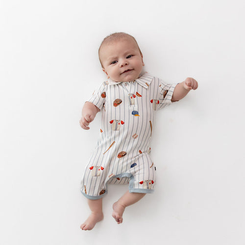 Young infant laying on a light neutral background wearing the Polo Shortall in Home Run