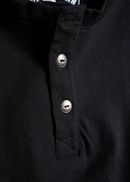 Close-up of a black henley shirt with two metal buttons, highlighting the textured fabric and button details.
