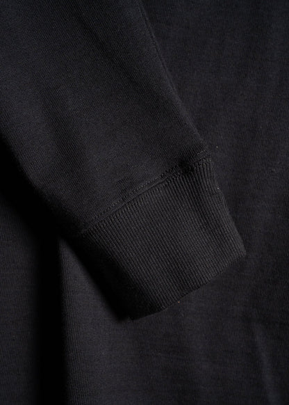 Close-up of a black sweatshirt sleeve showing ribbed cuff detail, highlighting the texture and fabric quality.
