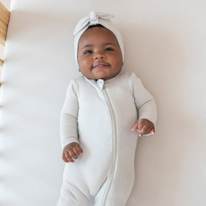 Baby wearing Kyte Baby Ribbed Zippered Footie in Oat