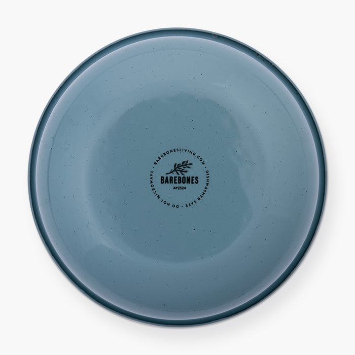 The bottom of a smoky blue rolled enamel bowl on a white background