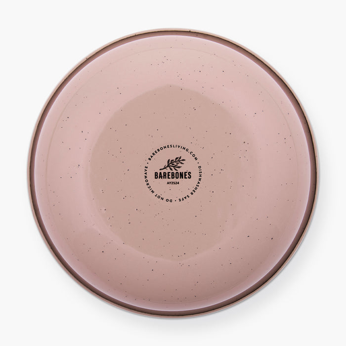 The bottom of a dusty rose rolled enamel bowl on a white background