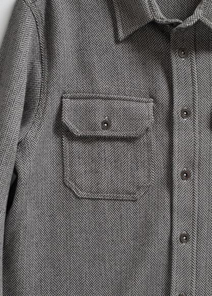 Gray herringbone shirt with buttoned front and chest pocket, showcasing detailed fabric pattern and classic design.
