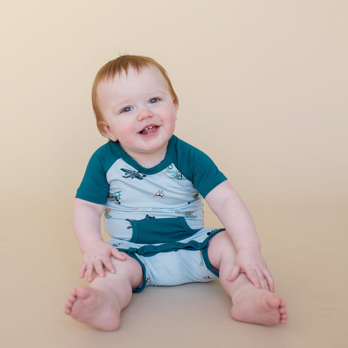 Young boy sitting wearing the Shortall in Take Off showing the Loch colored trim and pocket