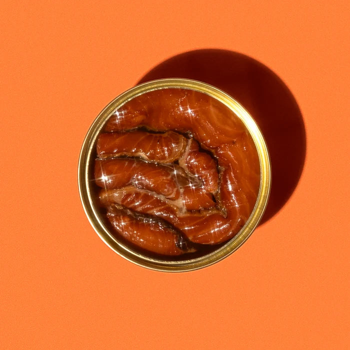 Canned food with a gold lid on an orange background