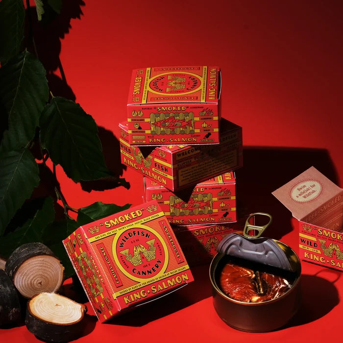 Several red and yellow products boxes on red background with open can with fish inside