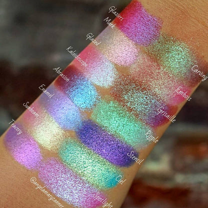 Top angled arm swatches on medium skin tone of Spotlight Glitter Multichrome Eyeshadow shifts compared to Glaziers Mark, Glazed, Kaleidoscope, Abrasion, Enamel, Sunbeam, Tracery, Carving, Emboss, Grisaille, Ripple, Stencil, Ciel