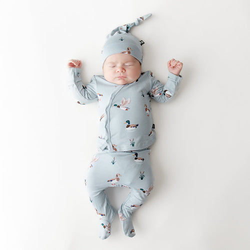 Sleeping newborn wearing the Take Me Home Set with Cap in Mallard Duck on a white surface