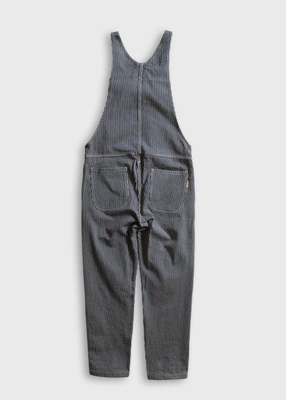 Blue and white striped overalls with pockets, laid flat on a white background, showcasing casual, vintage-inspired fashion.