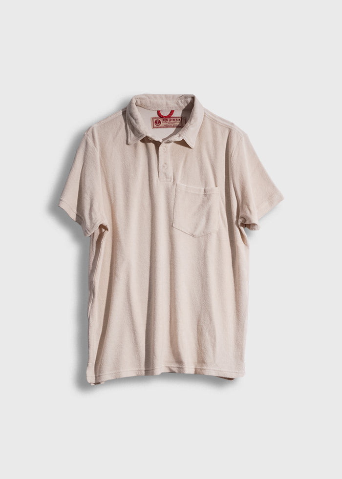Beige short-sleeve polo shirt with a chest pocket, displayed on a white background, featuring a red label inside the collar.