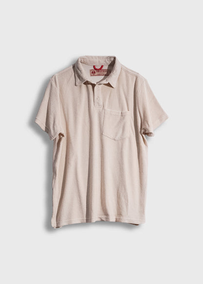Beige short-sleeve polo shirt with a chest pocket, displayed on a white background, featuring a red label inside the collar.