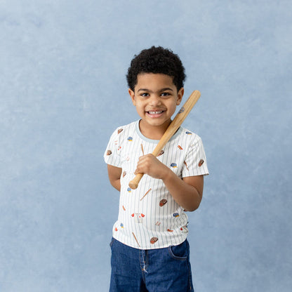 Young boy wearing the Toddler Basic Tee in Home Run holding a miniature wooden baseball bat
