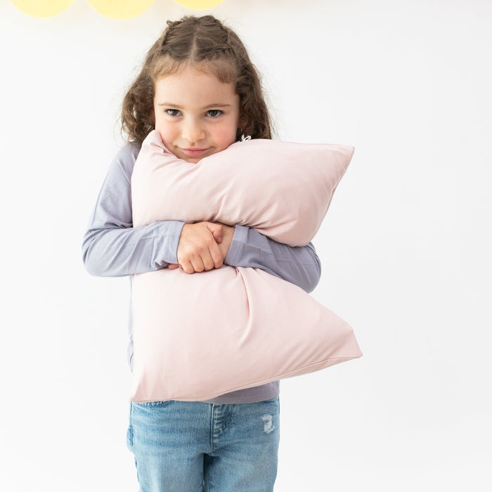 Girl holding Kyte Baby Toddler Pillowcase in Blush