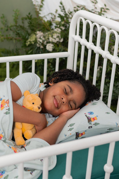 Young girl laying in bed on a Toddler Pillowcase in Winnie the Pooh Hundred Acre Wood with a matching blanket on top of her