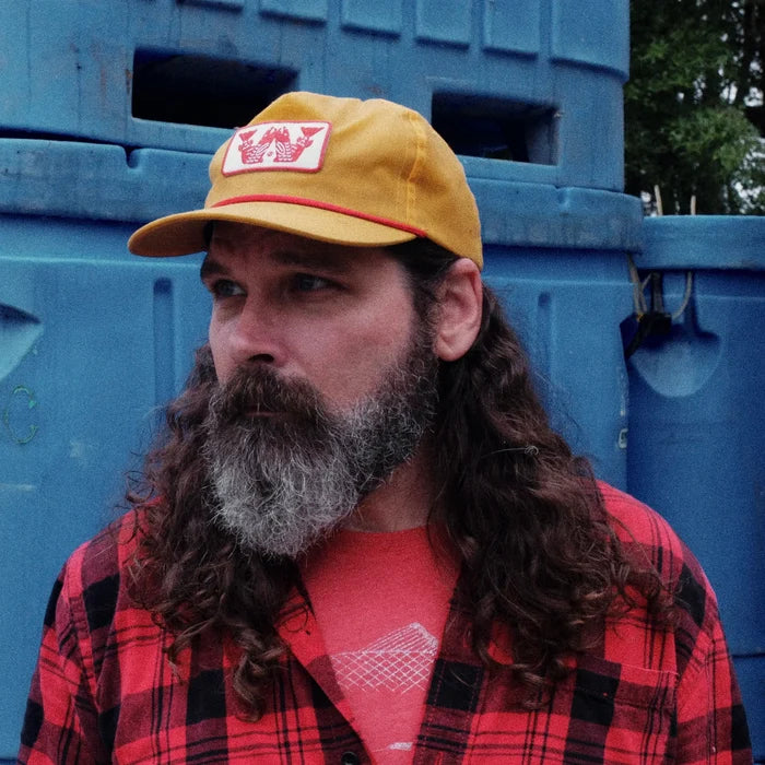 Man wearing a yellow cap and red plaid shirt in front of blue storage containers
