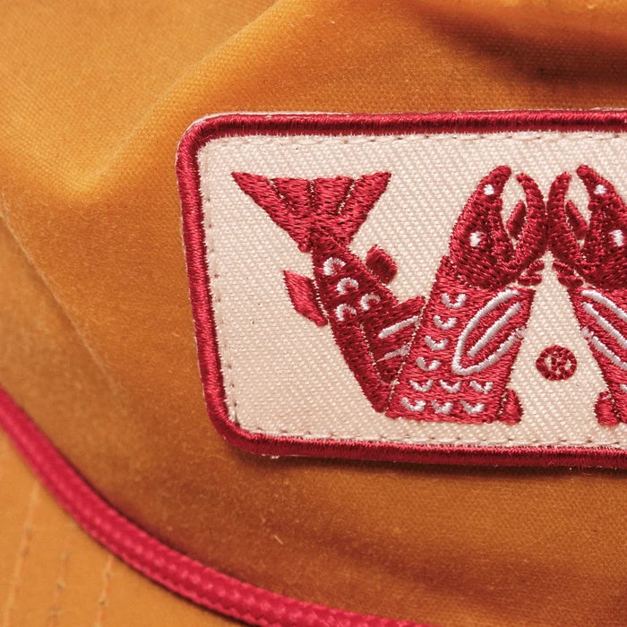 Brown cap with red embroidered salmon design on a beige background