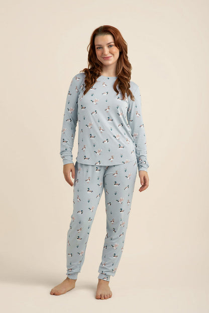 Woman wearing a light blue pajama set with a duck pattern on a beige background