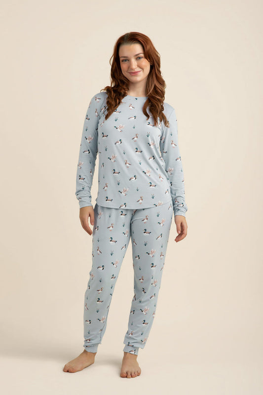 Woman wearing a light blue pajama set with a duck pattern on a beige background