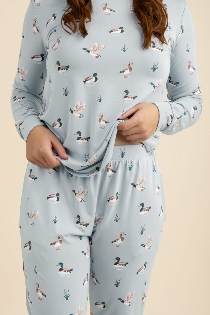 Light blue pajama set with duck pattern worn by a person on a beige background