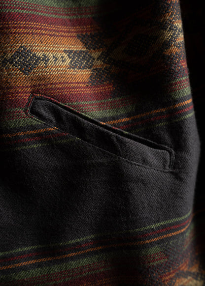 Close-up of a wool jacket pocket with a colorful, geometric pattern in red, green, and orange hues.