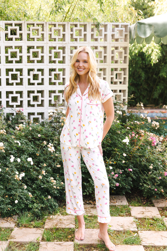 Woman wearing a floral pajama set standing in a garden.