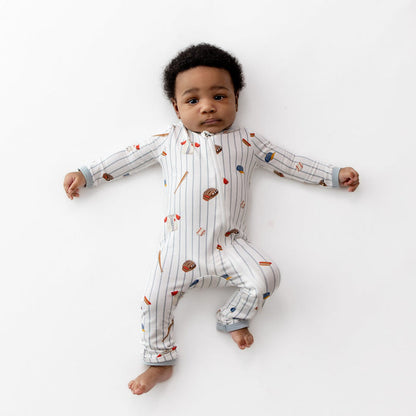 Infant lying on a white surface wearing the Zippered Romper in Home Run