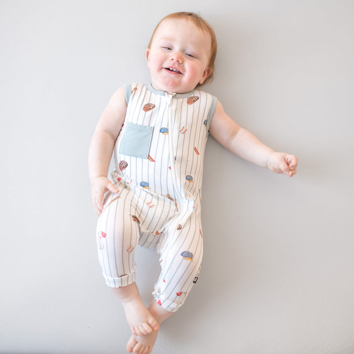 Smiling toddler wearing the Zippered Sleeveless Romper in Home Run